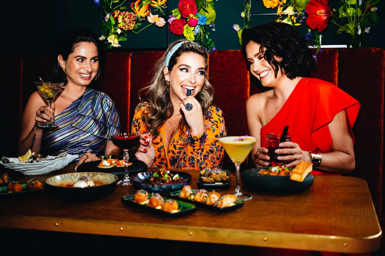 Drie gasten in de rode booth van Miss Johnsen met cocktails